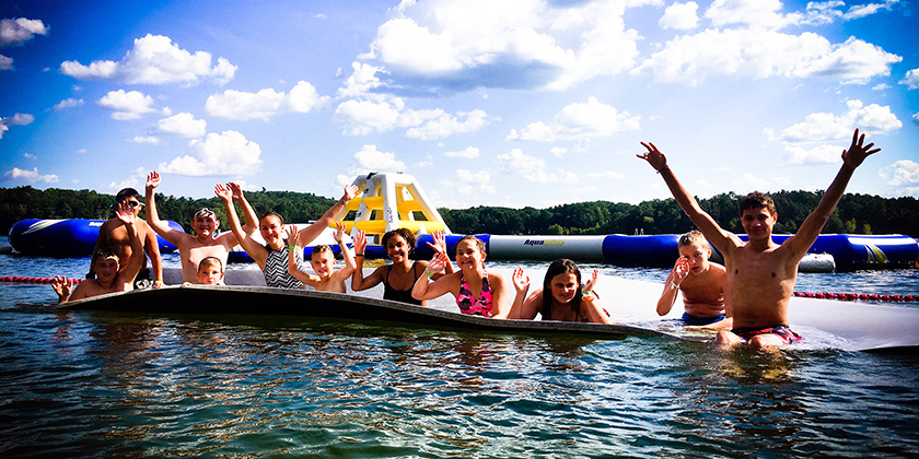 A group of kids playing on a raft at Camp Klotty Pine